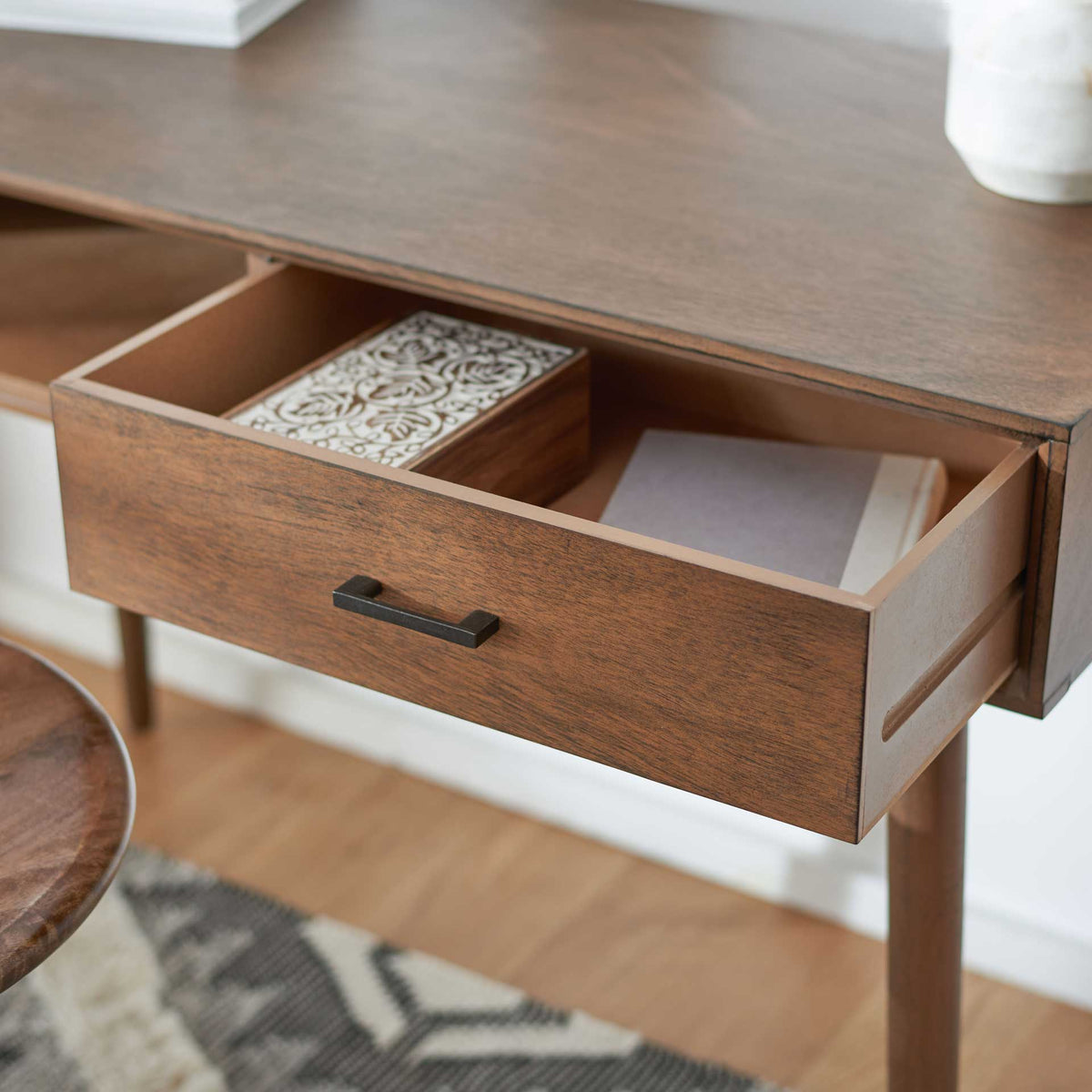 Open brown desk drawer holds notebooks and small essentials below the worktop