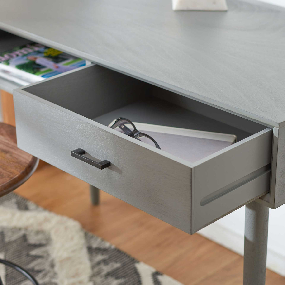 Spacious gray desk drawer opens to organize notebooks and reading glasses