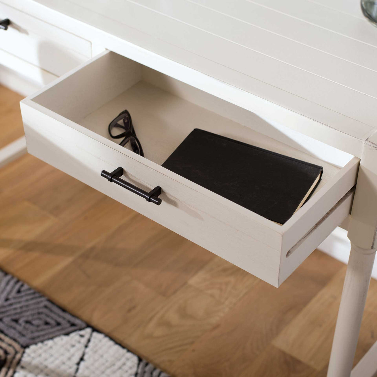 An open white drawer neatly holds everyday items beneath the desk's grooved work surface
