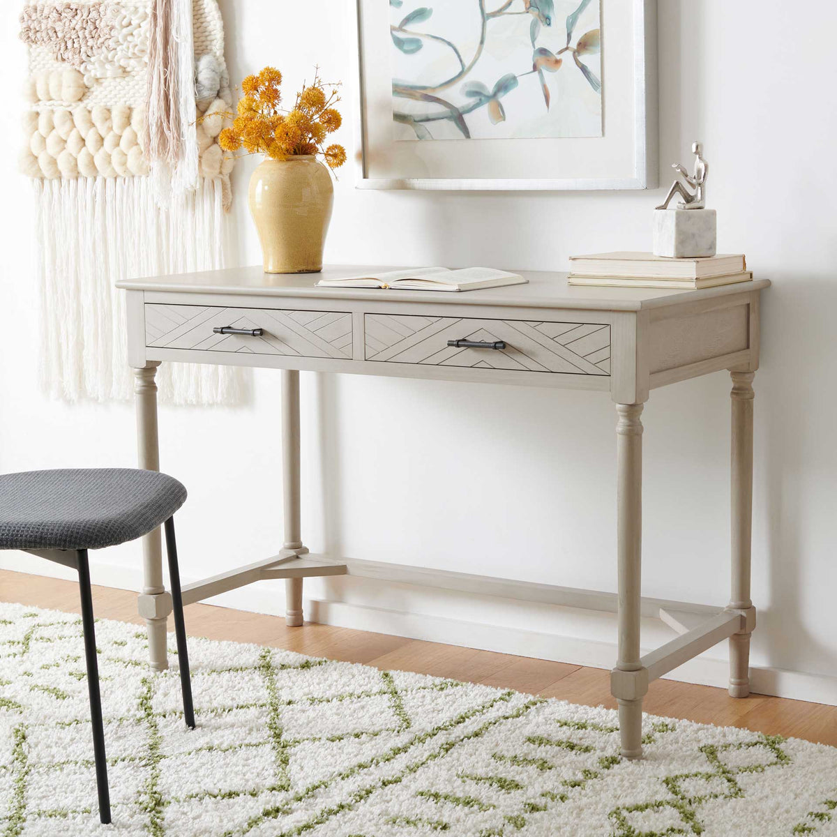 A warm taupe desk combines chevron-patterned drawers with an open, graceful base