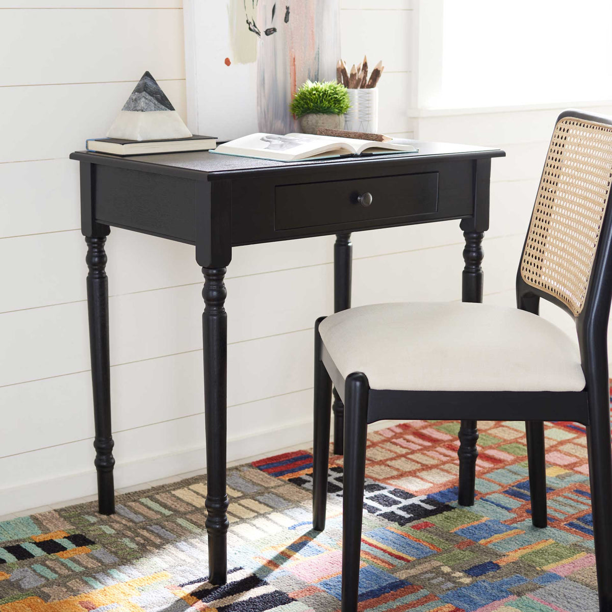 Black desk with a practical writing surface, discreet drawer, and refined turned legs