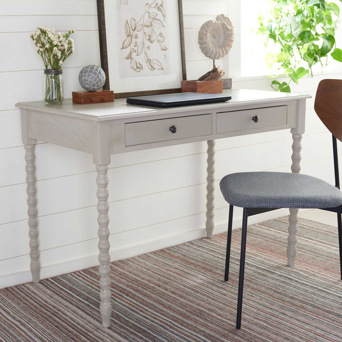 A slender taupe writing desk with two drawers brings timeless charm to a bright workspace