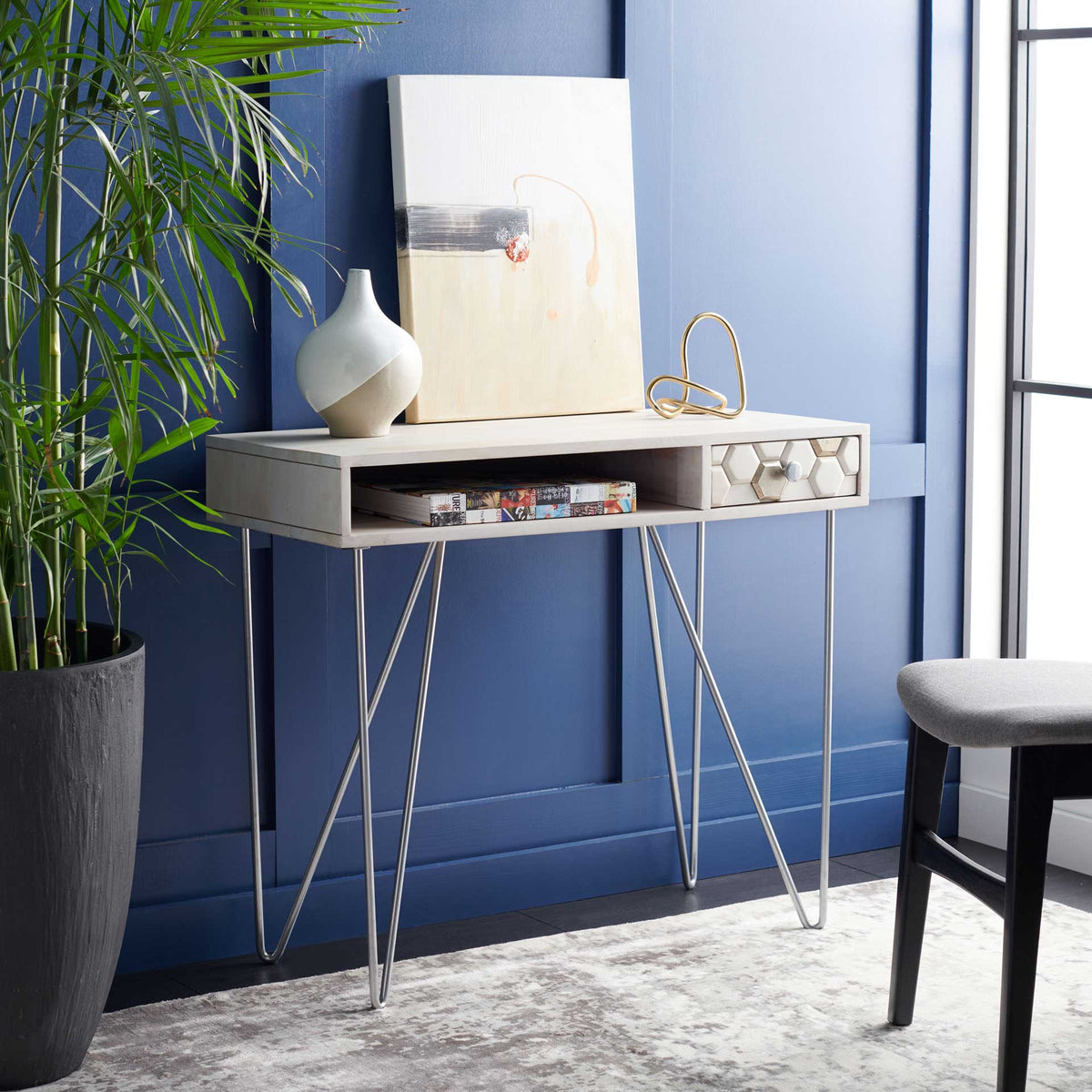 An open cubby keeps reading materials handy beneath the whitewashed top and silver-accented drawer.