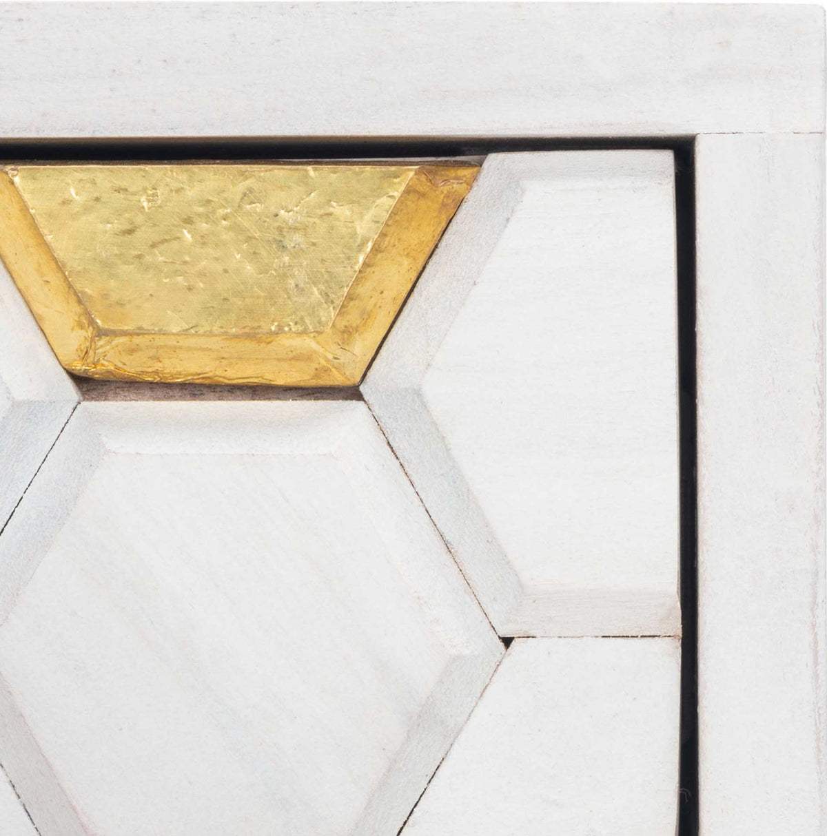 Carved white hexagons meet warm brass inlays on the desk's textured drawer front.