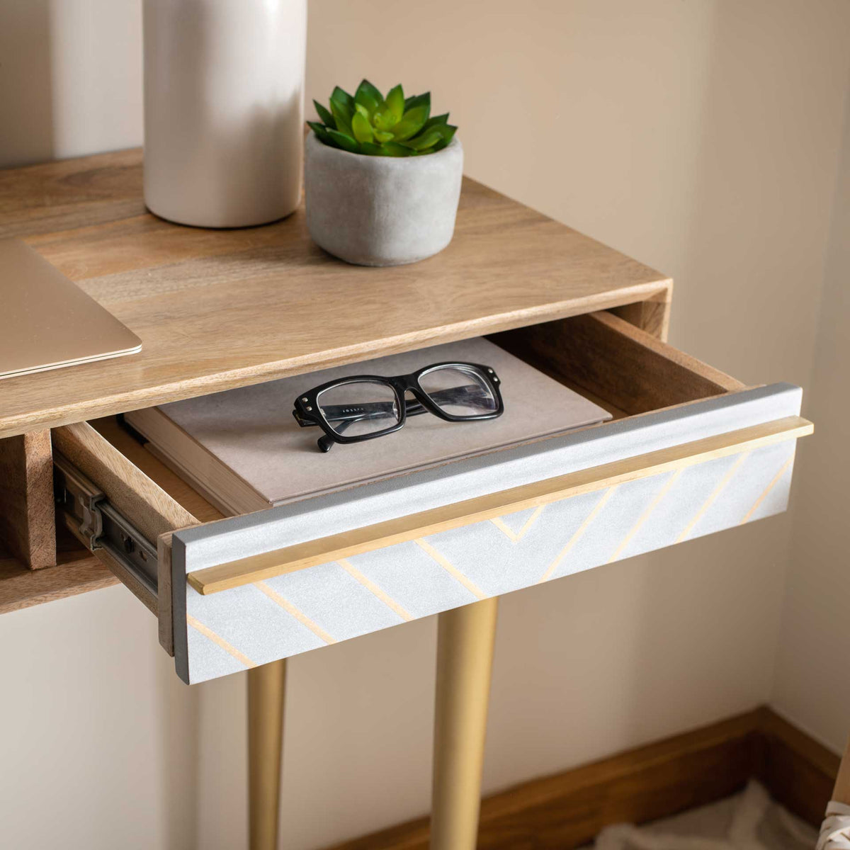 An open drawer reveals space for small essentials beneath the wood top, framed by a brass-accented cement front