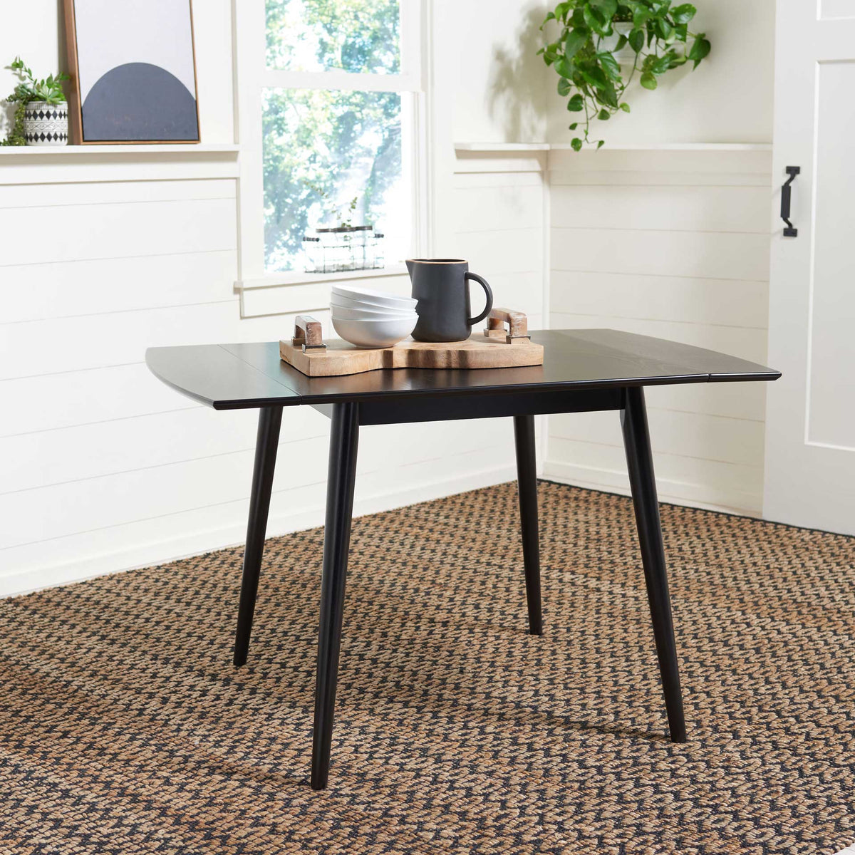 Matte black drop-leaf dining table opens wide on four slender, outward-angled legs