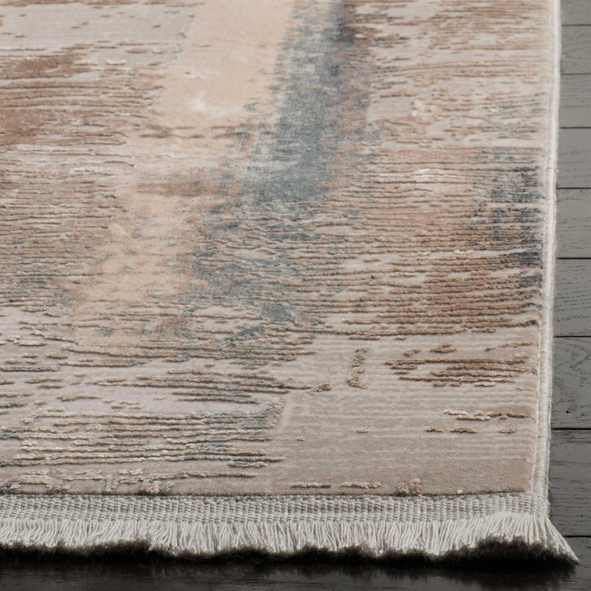 Short cream fringe edges a low-profile rug with textured beige and muted blue strokes