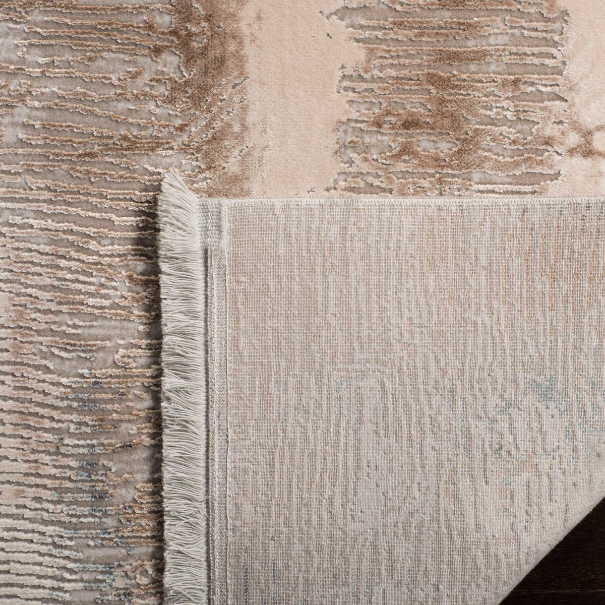 Woven cotton backing and a short fringed edge finish the softly textured abstract rug