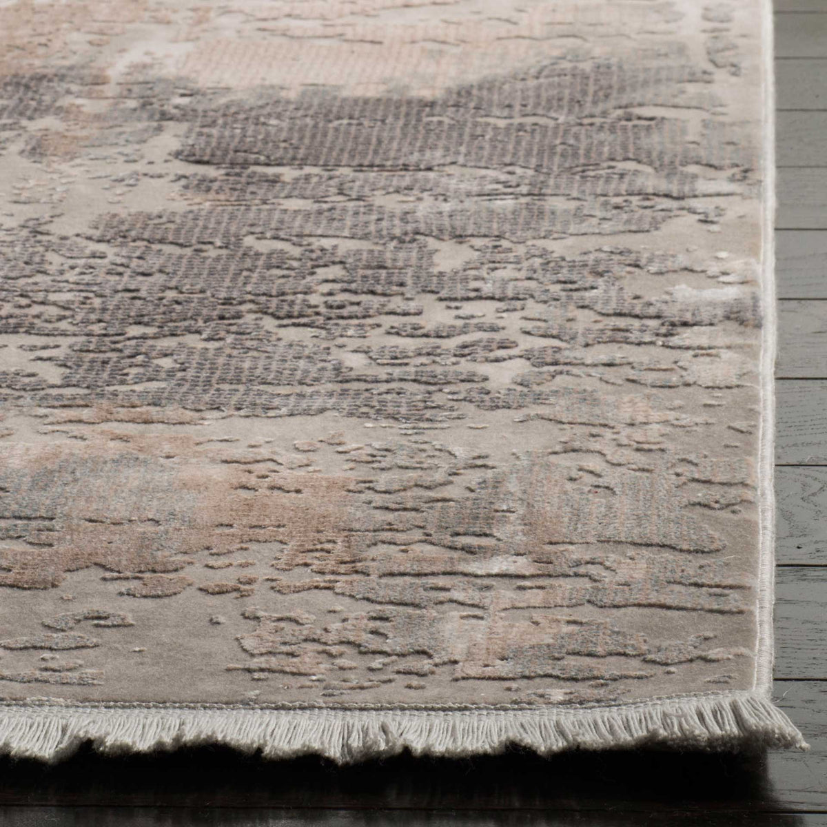 Short fringe accents a neatly finished corner and the rug's textured beige and gray abstract pile