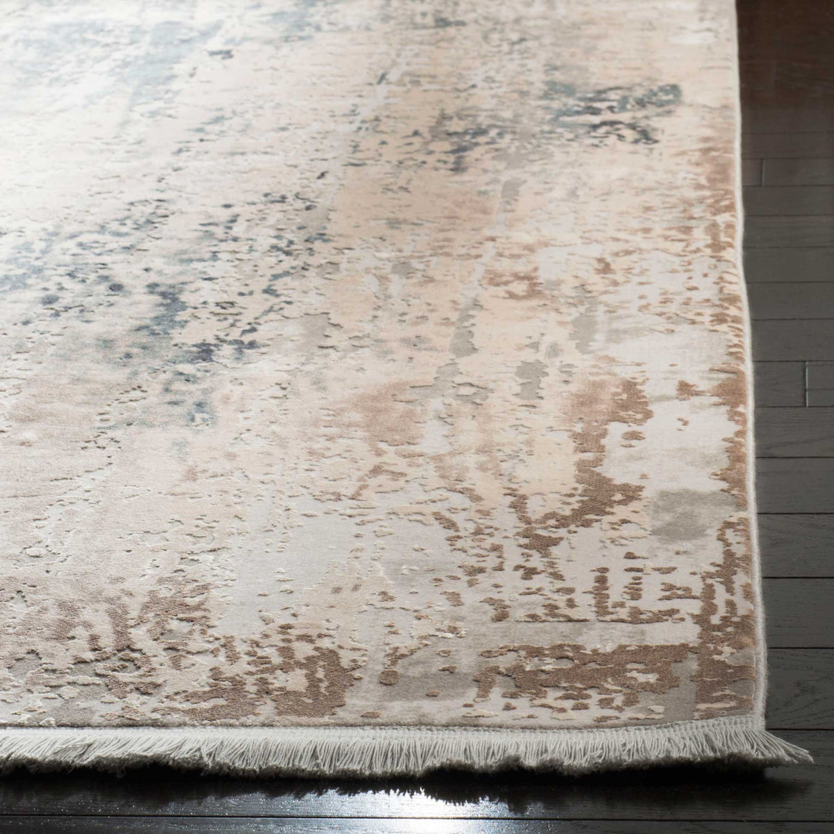 Low-profile rug with painterly beige and blue accents and a delicate fringe