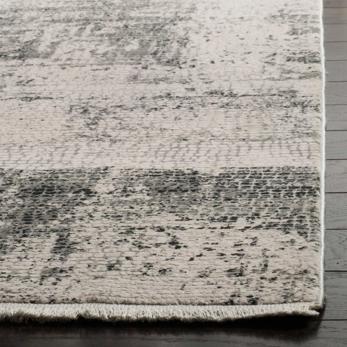 Gray markings, short pile, and a neatly finished edge bring texture to this beige rug.