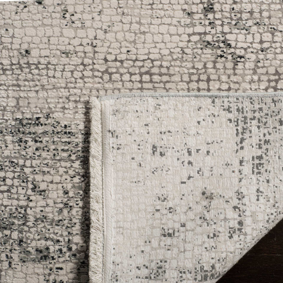 A folded corner reveals the rug's textured backing and contrasting woven surfaces.