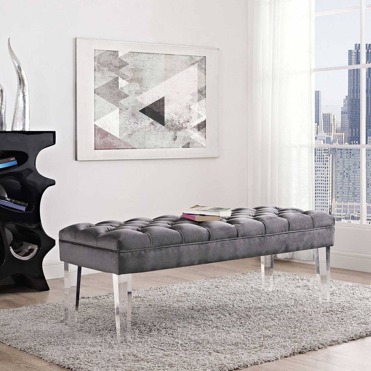 A tufted gray velvet bench adds soft seating and modern clear legs to a bright room
