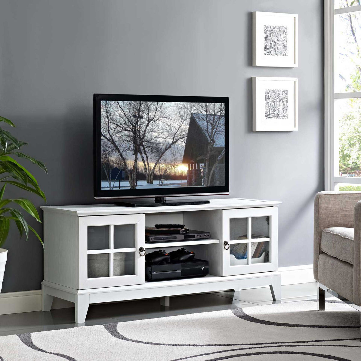 White TV stand supports a flat-screen TV and organizes electronics on open shelves and behind glass doors