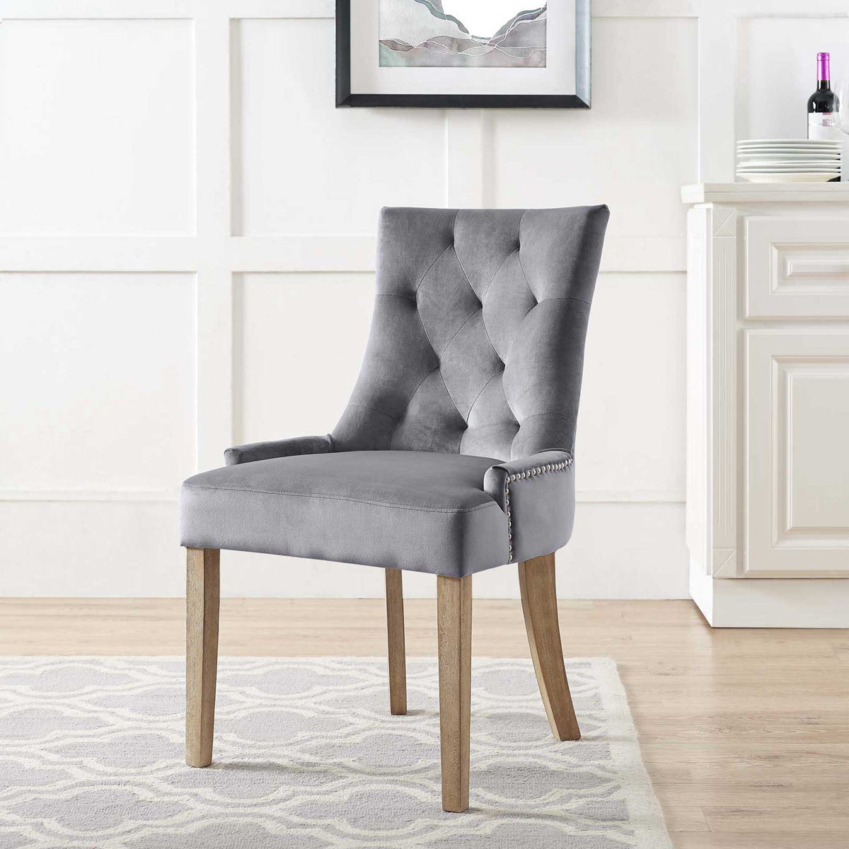 Plush gray velvet and diamond tufting soften a dining area, complemented by natural wood legs