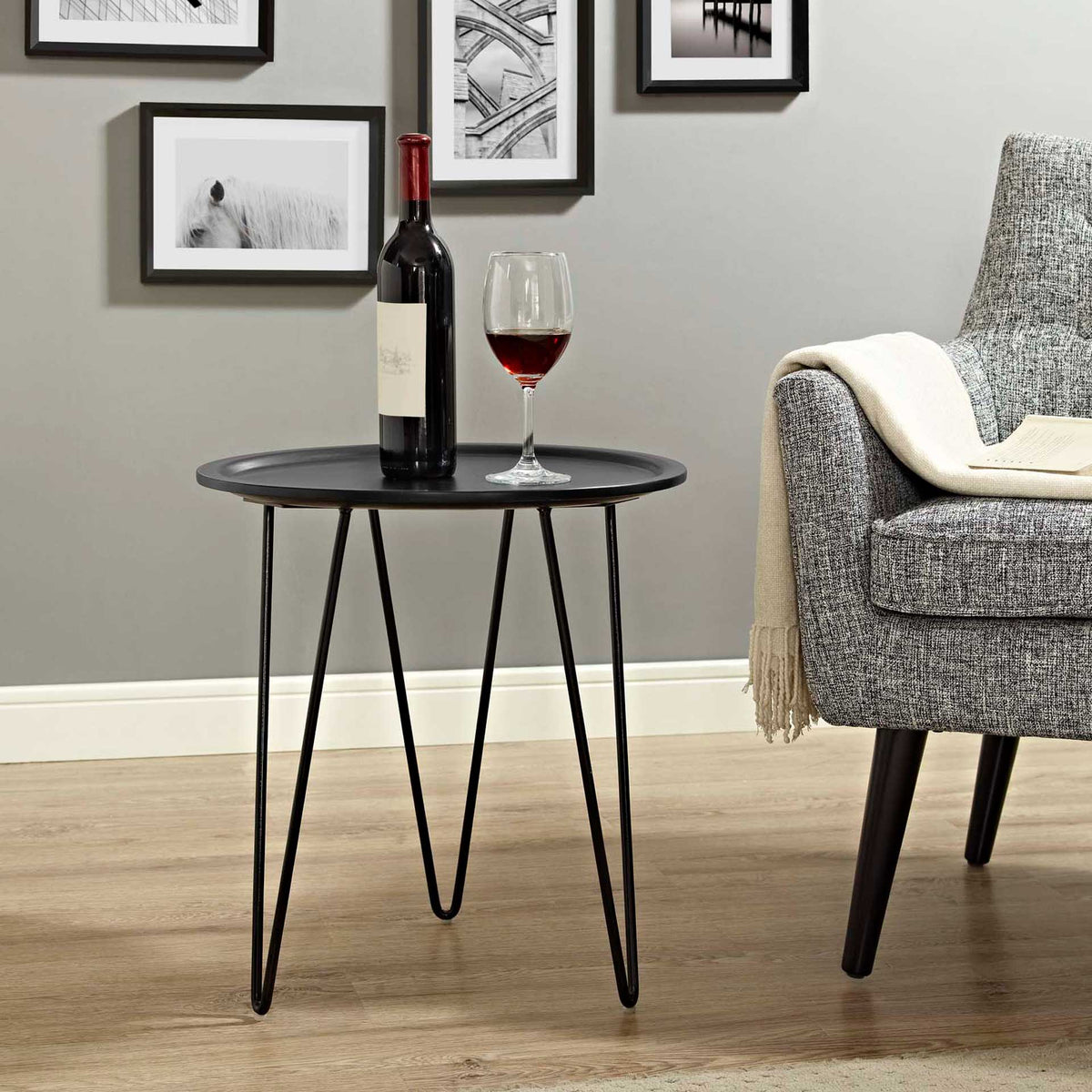 Black hairpin-leg side table holds drinks beside an upholstered chair