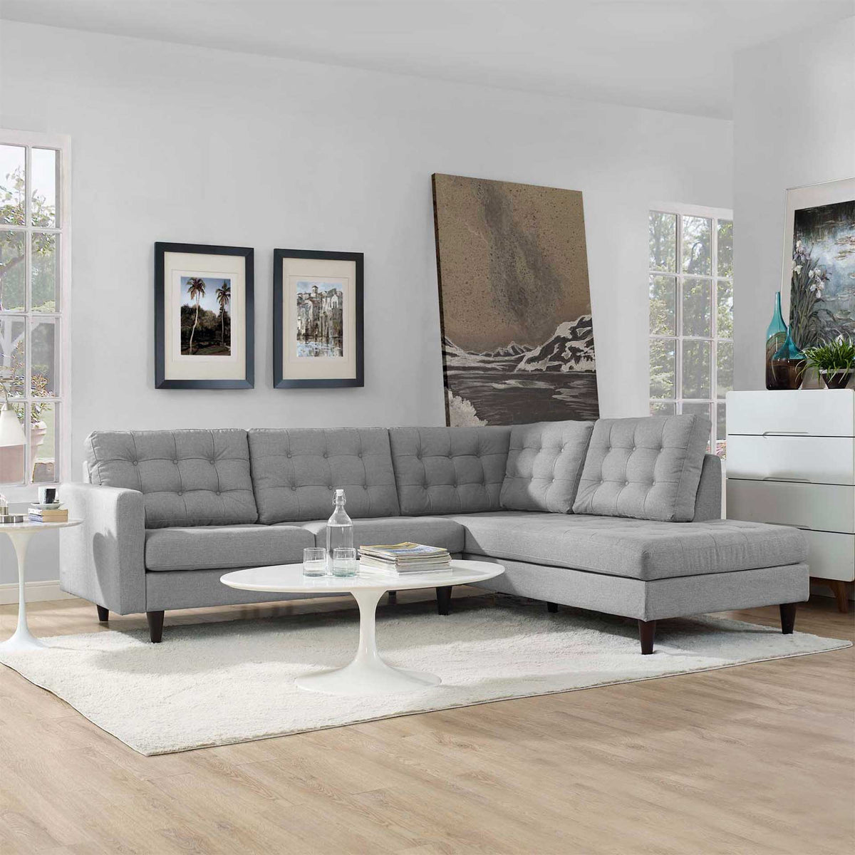 A light gray sectional offers a tufted loveseat and lounging chaise in a sunlit room