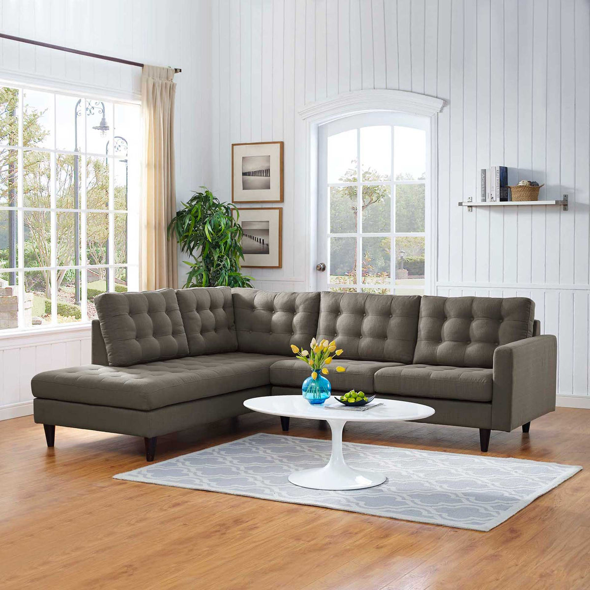 Warm gray sectional stretches across a bright room with a button-tufted chaise and loveseat