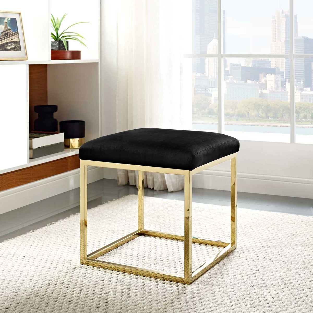 A black velvet ottoman brings inviting comfort and gold shine to a bright room