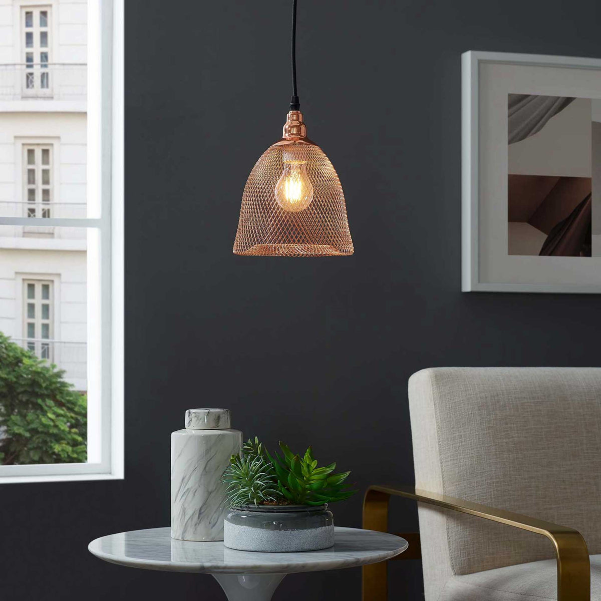 A visible bulb casts a warm glow through the rose gold wire shade over a cozy seating area