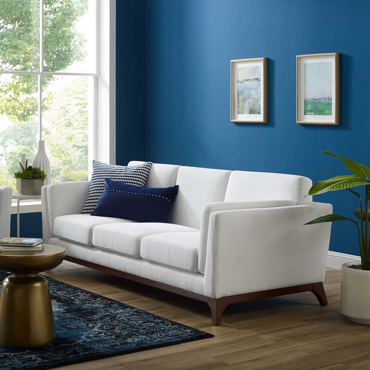 A roomy white sofa with flared arms and soft cushions complements rich blue decor
