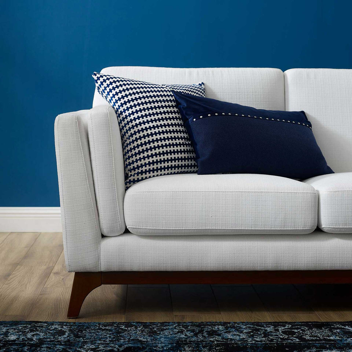 Textured white upholstery and plush cushions bring soft comfort to the sofa's flared arm