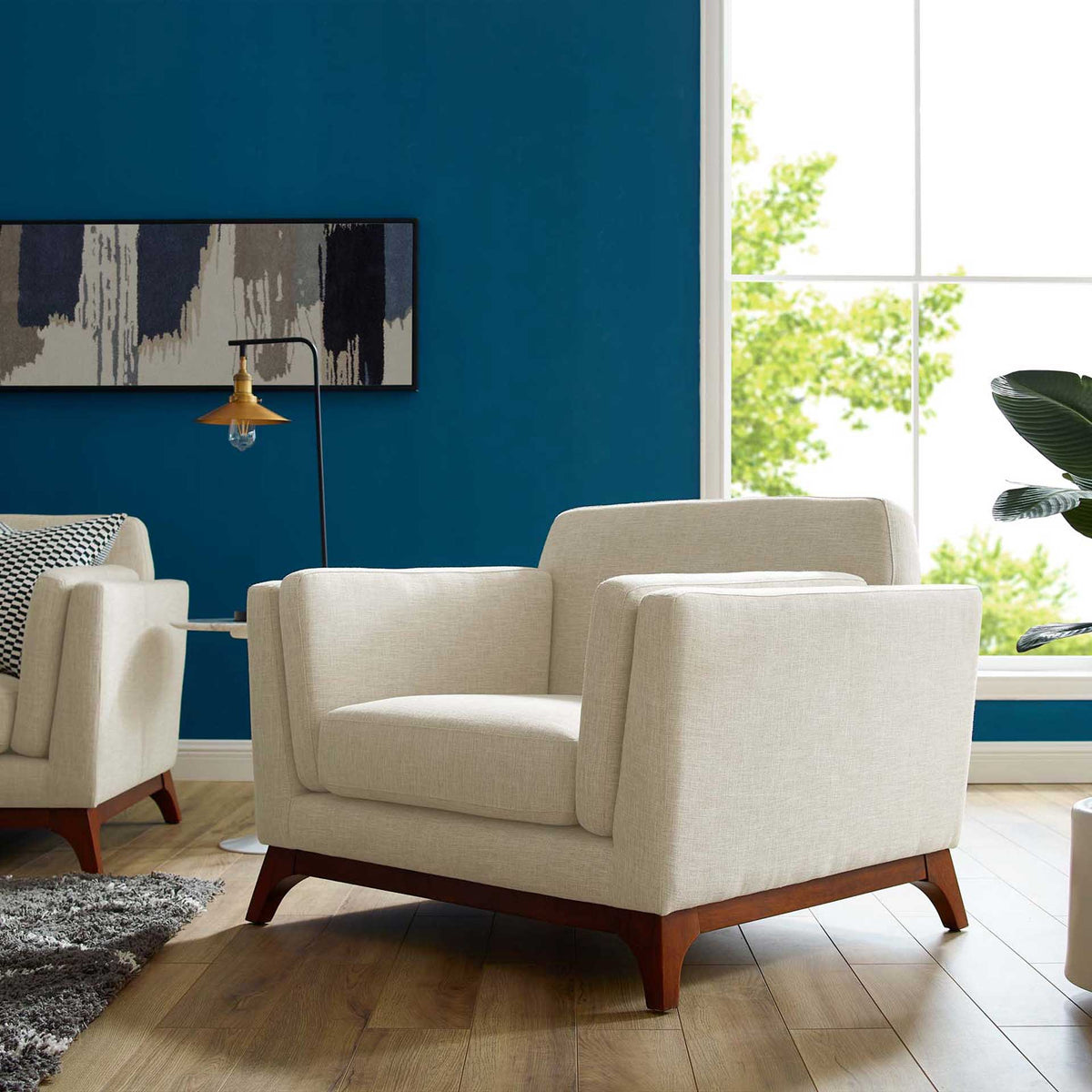 A roomy beige armchair brings plush cushions and warm wood accents to a bright living space.