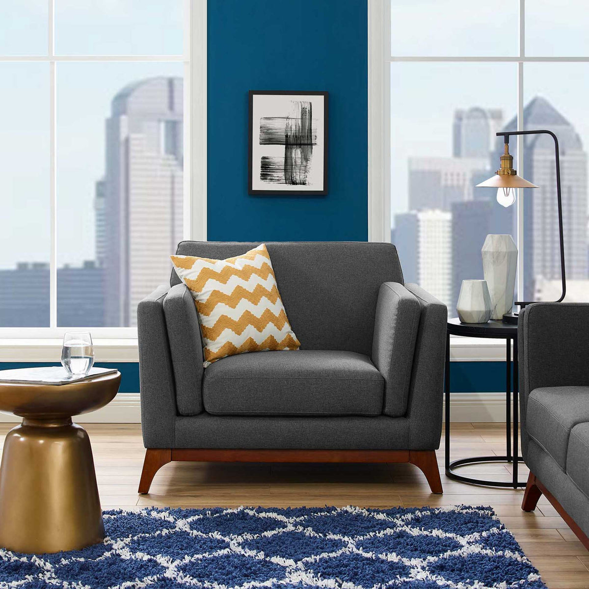 A plush gray armchair with tapered wood legs brings soft contrast to a bright living room.