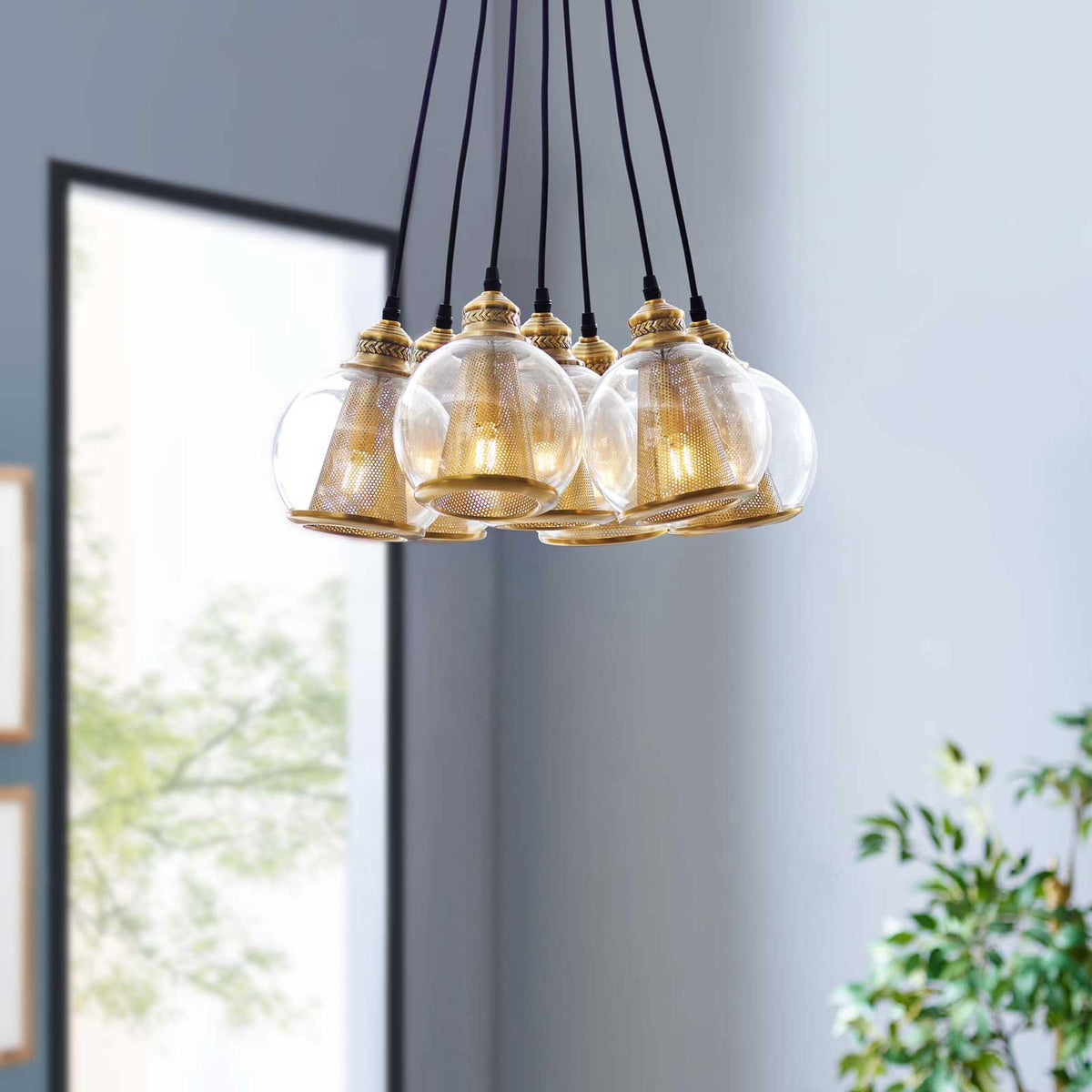 A cluster of glass globes and gold cone shades hangs from black cords, adding sculptural appeal to the room.