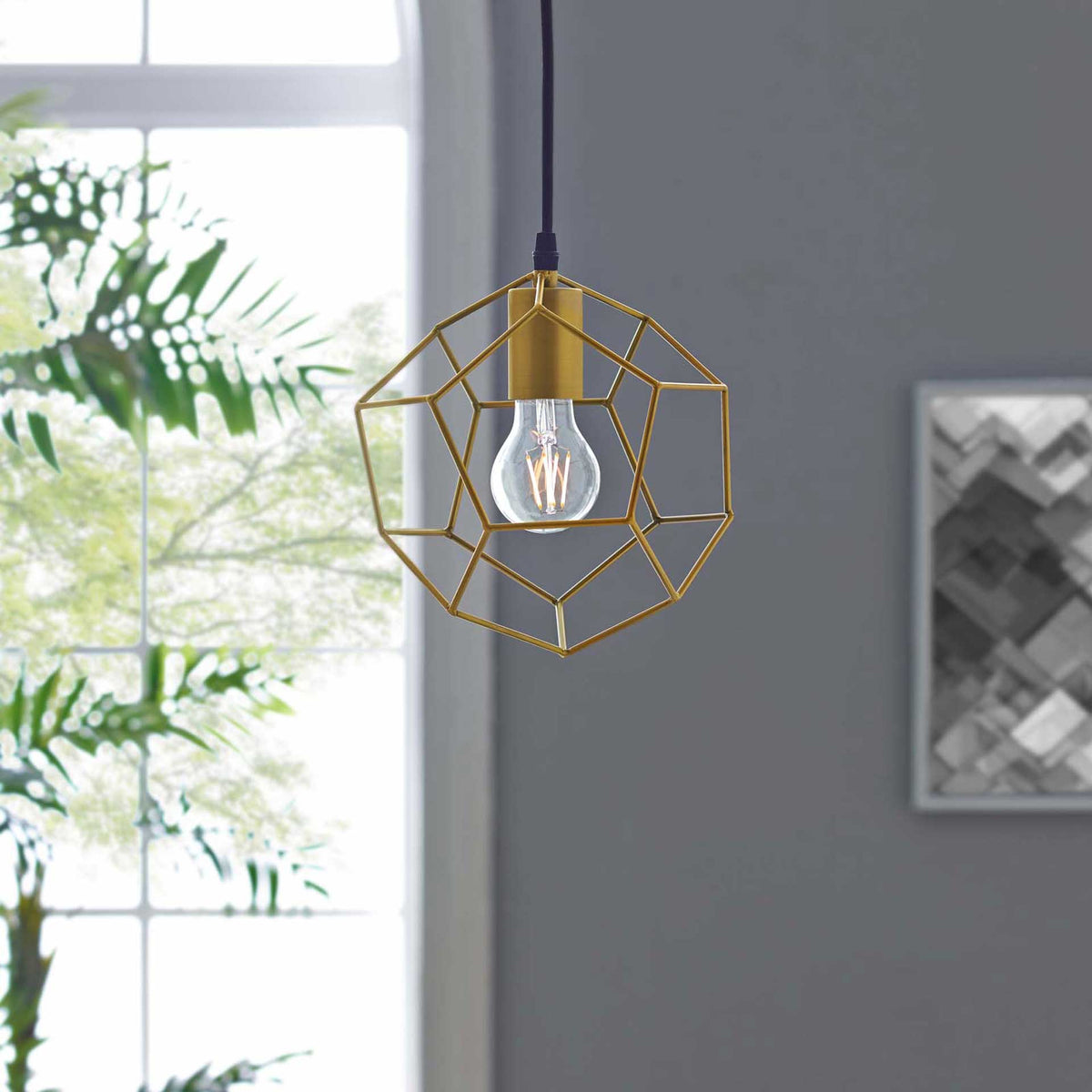 Gold geometric wirework adds an airy sculptural accent beside a bright window