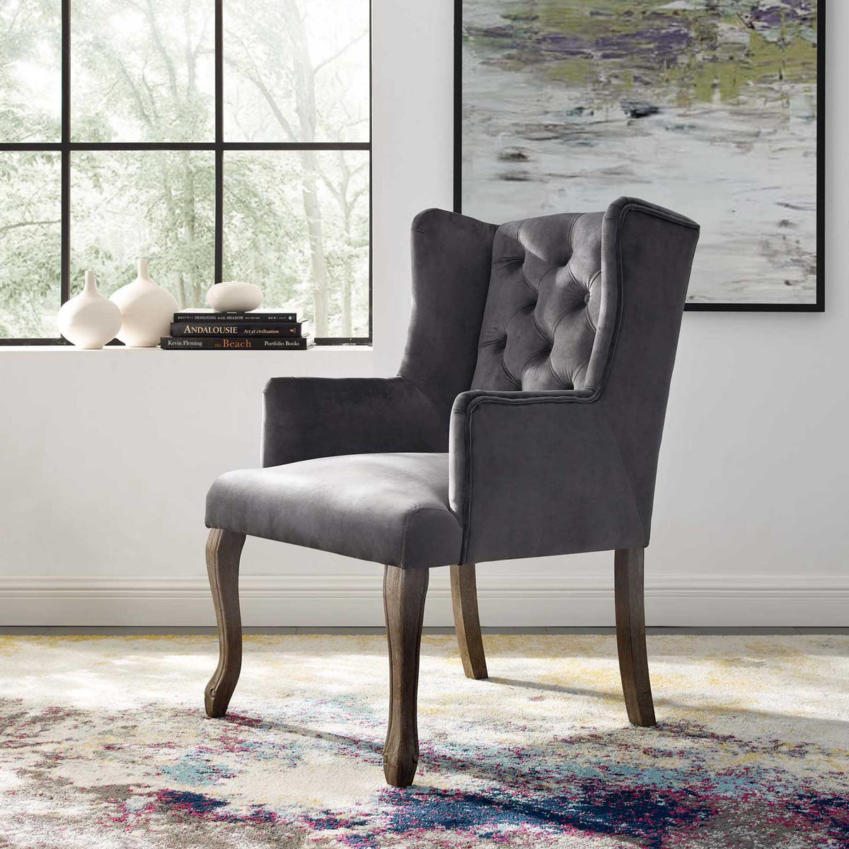 A tufted gray velvet wingback and weathered wood legs lend classic charm to a bright living space