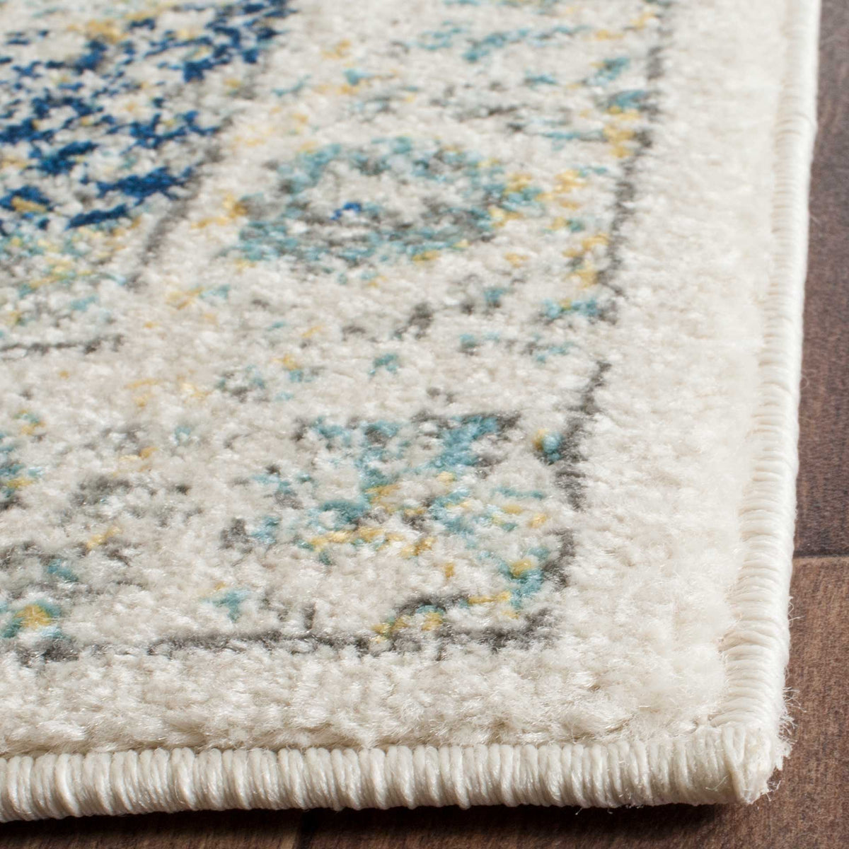Soft ivory pile frames blue, teal and gold details along a neatly bound rug corner