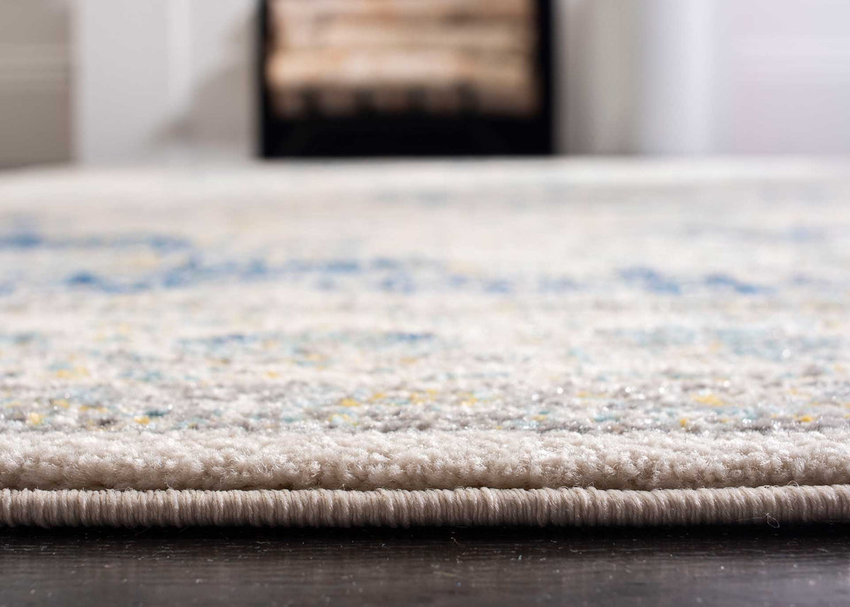 Dense ivory pile shows flecks of blue and gold above a tightly wrapped rug edge