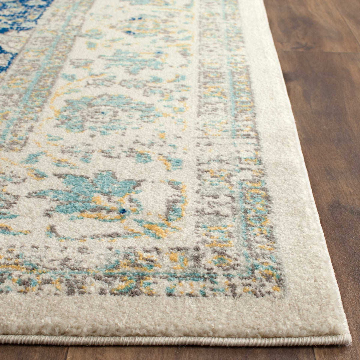Aqua and gold floral motifs brighten ivory pile alongside a thick, neatly bound edge