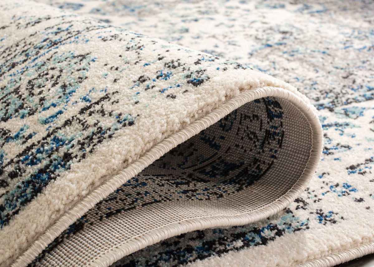 Soft ivory pile folds back to reveal tightly woven backing beneath blue and gray pattern