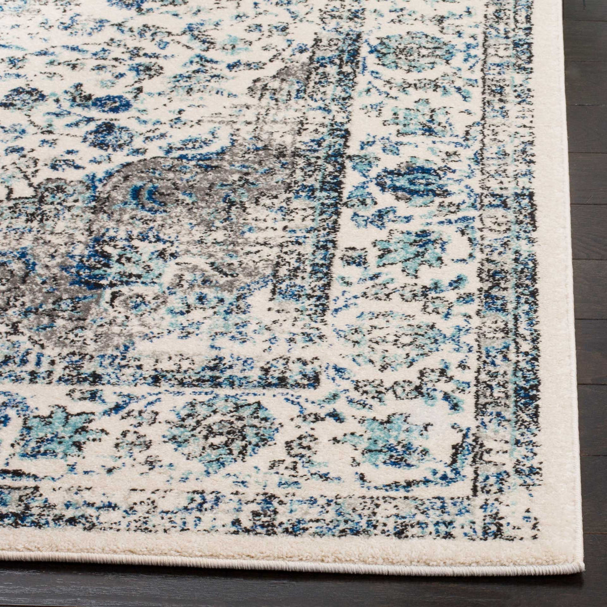 An ivory rug pairs blue floral scrolls with a distressed gray field and tidy binding