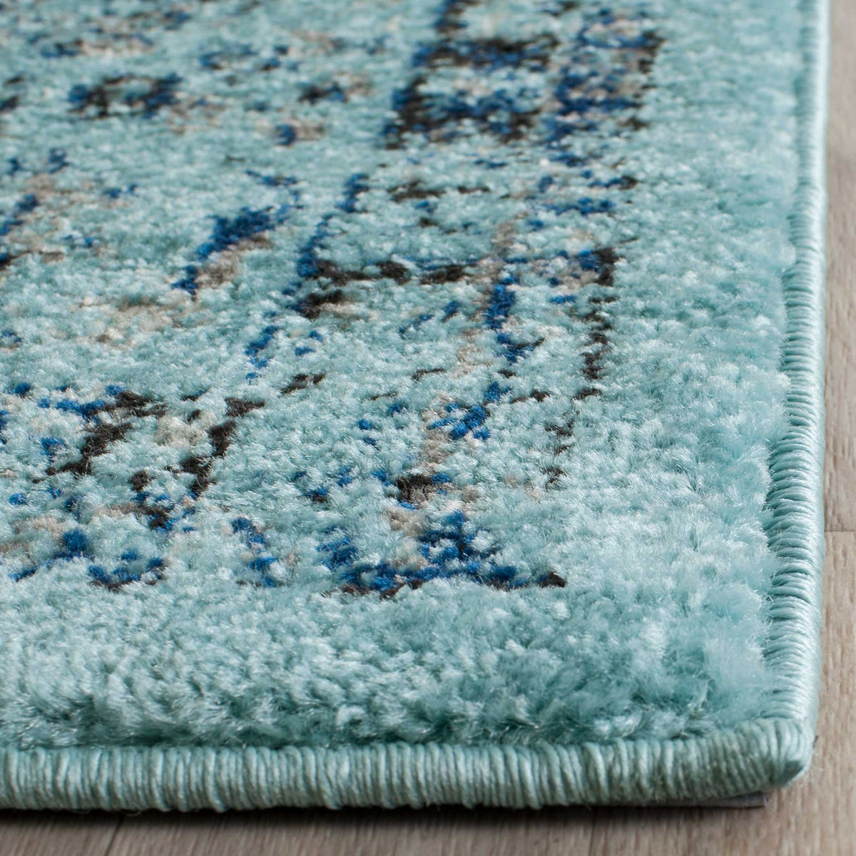 Pale aqua pile and subtle navy floral details lead to a neatly bound edge