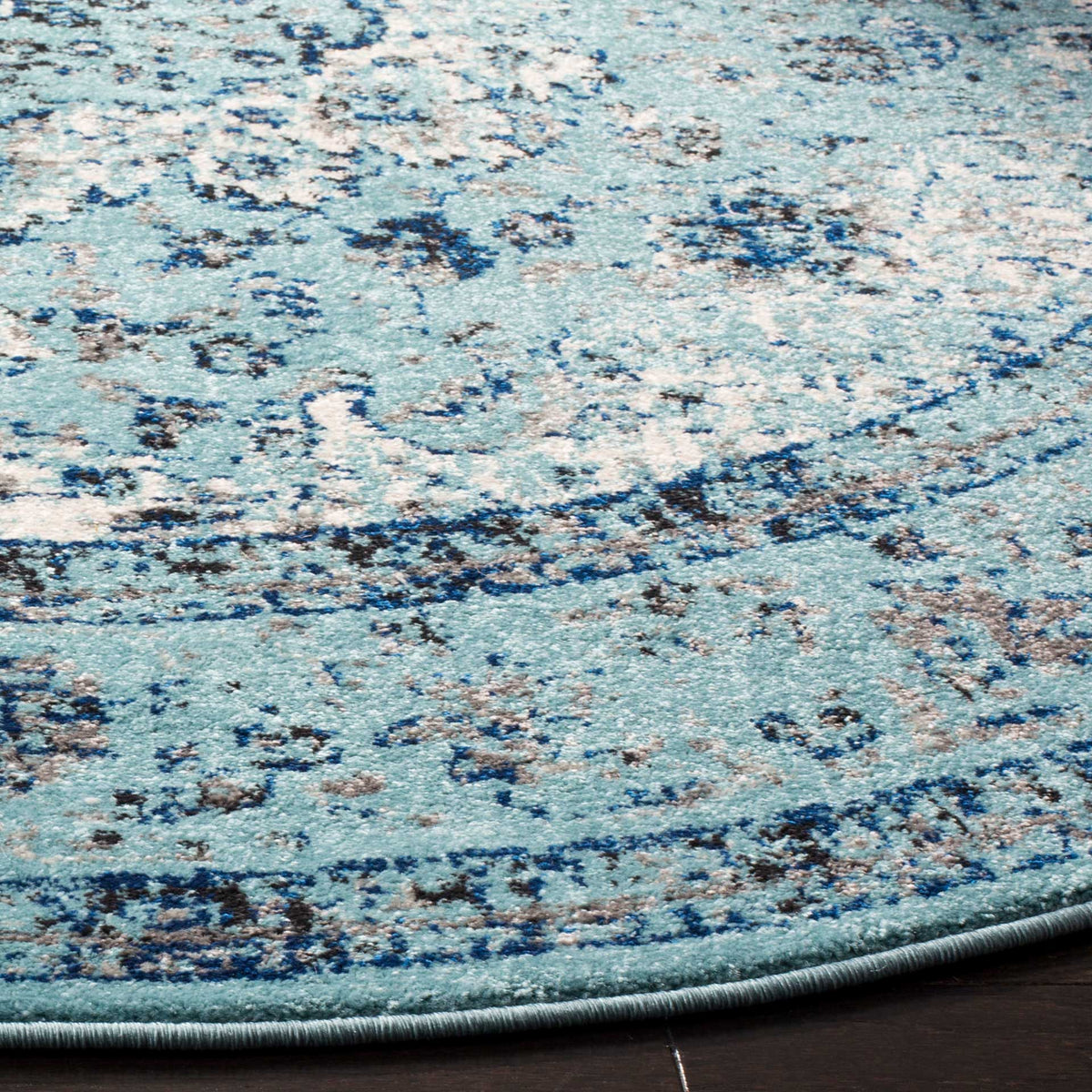 Distressed navy floral motifs sweep across the light blue pile and end in a curved bound edge.