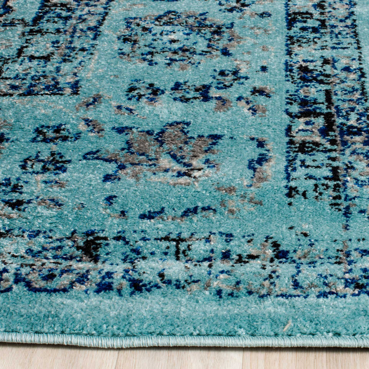 Dark blue scrollwork accents the turquoise pile and neatly finished edge
