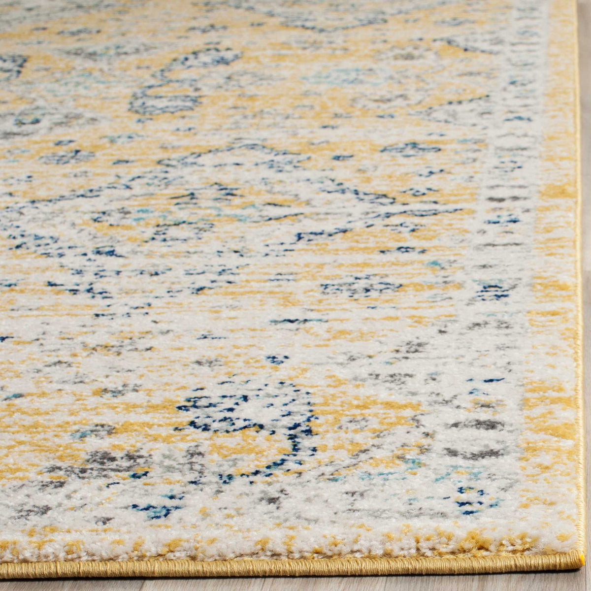 A gold-bound edge finishes ivory pile with softly distressed gold and blue floral details.
