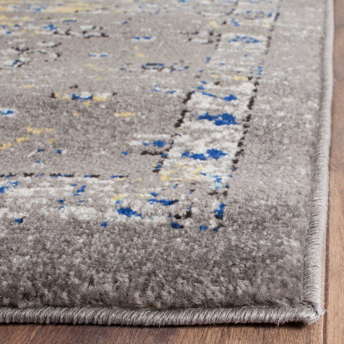Dense gray pile and a neatly bound corner highlight flecks of ivory, blue, and soft yellow.