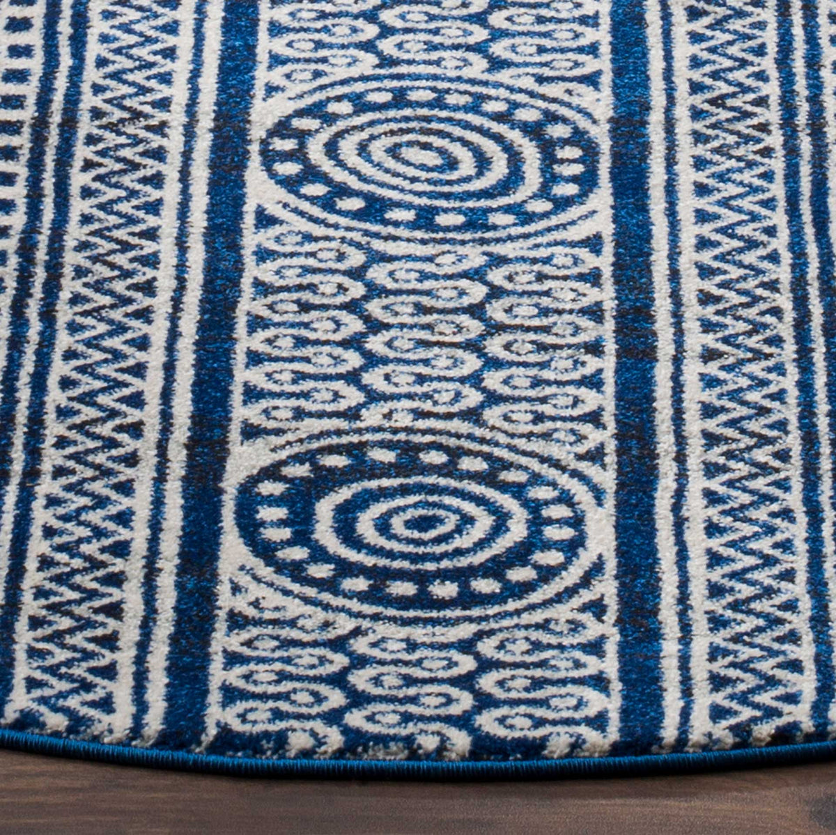 Royal blue and ivory pile displays concentric medallions, zigzag borders, and a bound edge