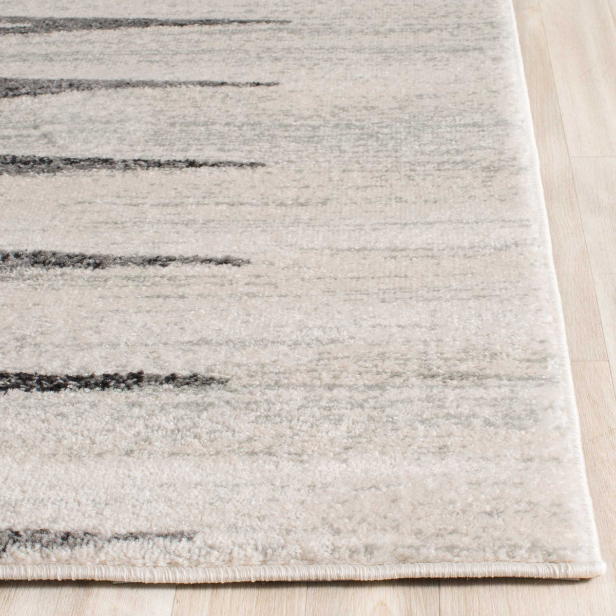 Bound ivory rug edge frames soft gray geometric lines and a short, textured pile.