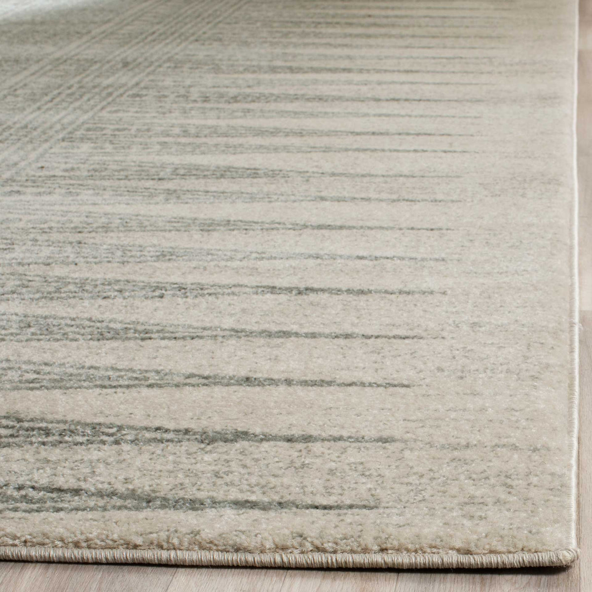 Neatly bound edge and gently faded silver stripes highlight the soft ivory rug pile.