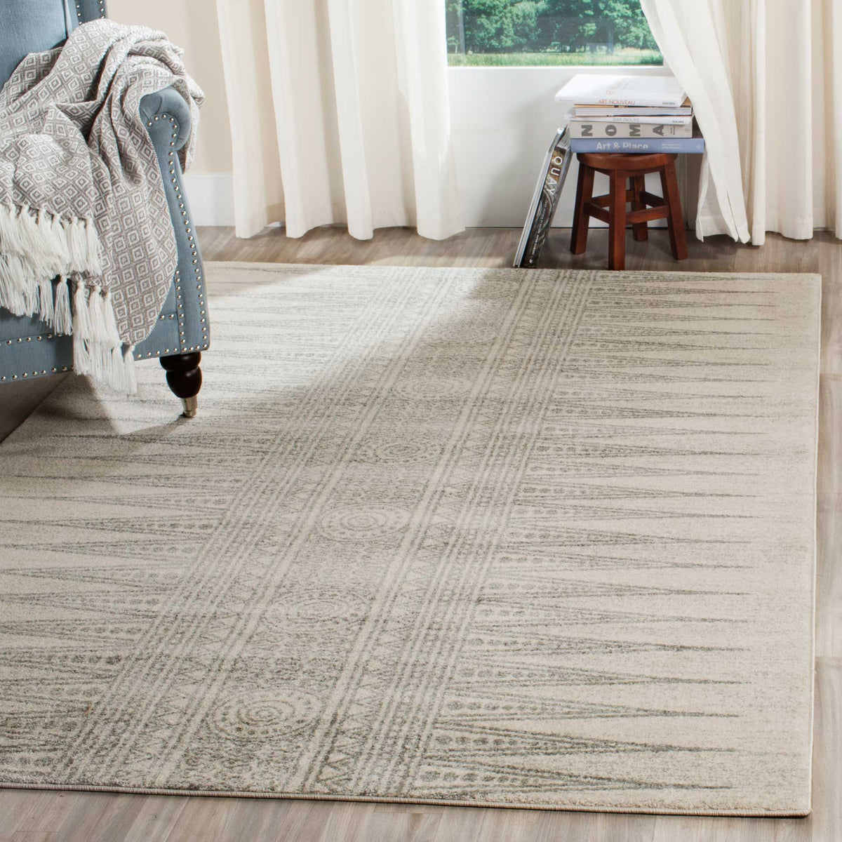 Ivory and silver geometric rug adds subtle pattern beneath a blue accent chair.