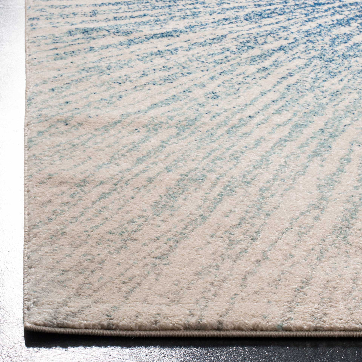 A bound ivory edge outlines this softly textured rug with pale blue starburst rays.