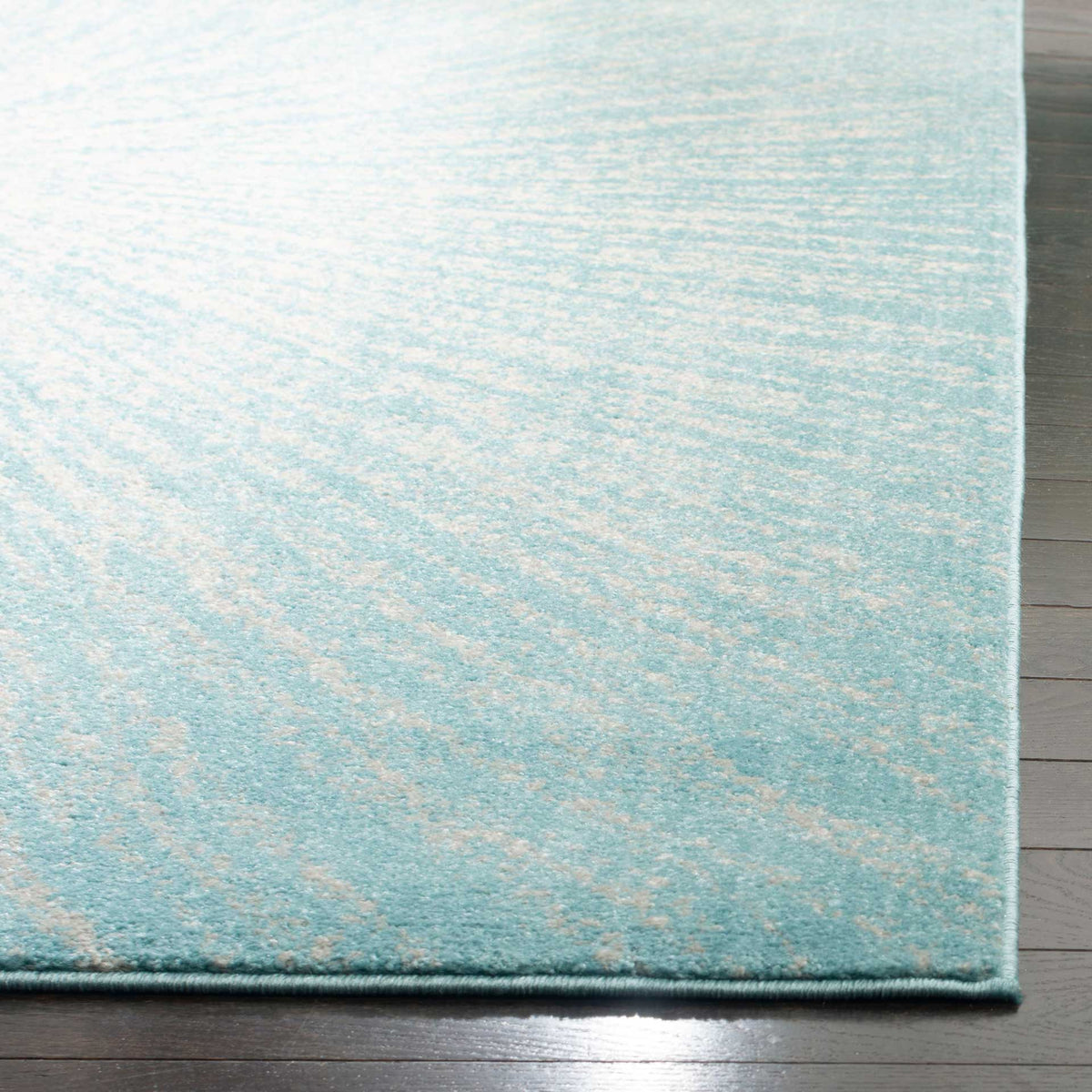 A neatly bound edge finishes the aqua and ivory rug's softly textured pattern.