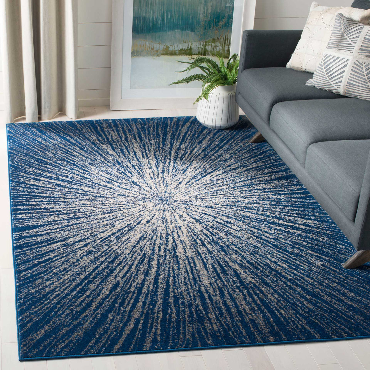A navy and ivory starburst rug grounds a gray sofa and energizes a bright living space.