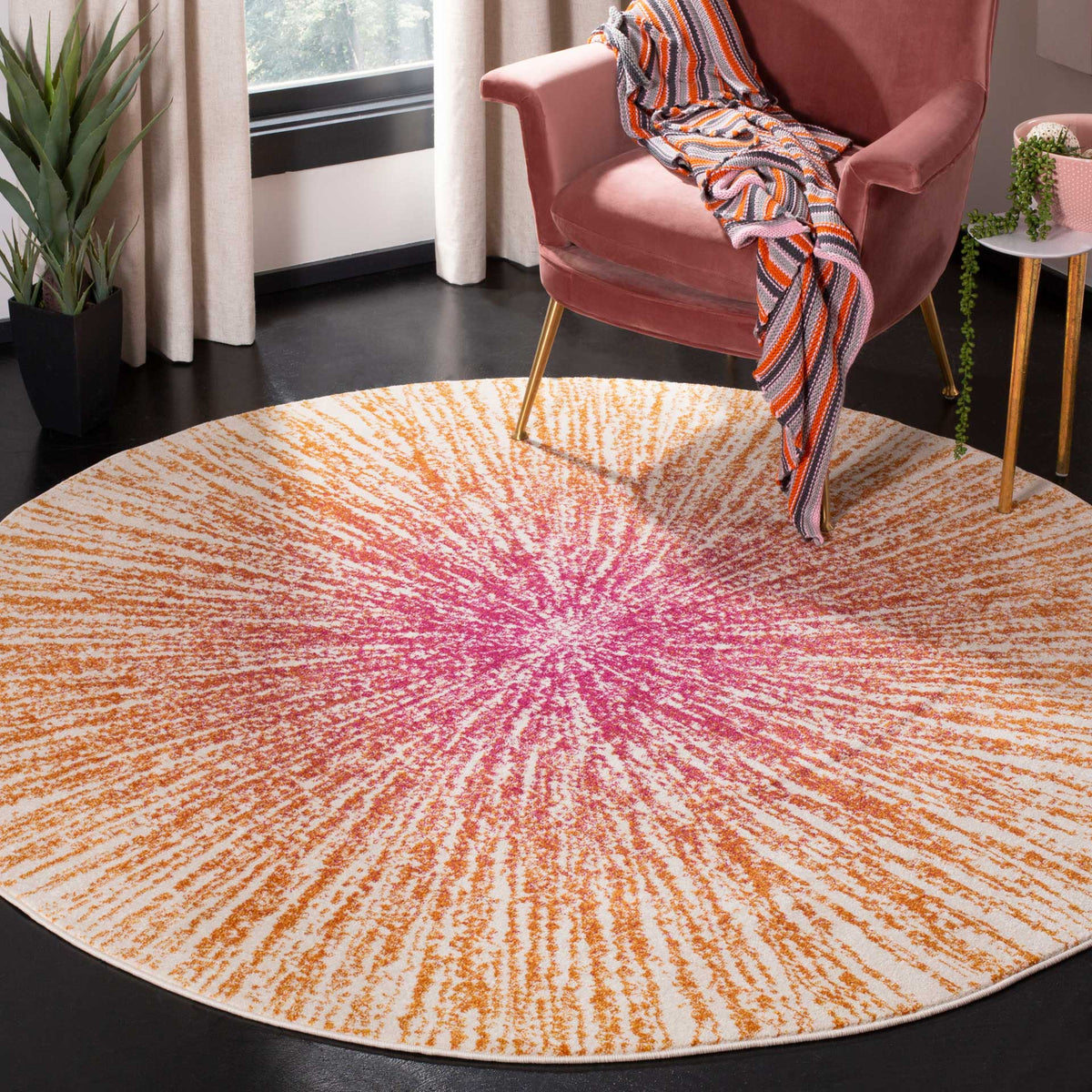 A cream round rug with vivid fuchsia and orange rays brightens a seating area