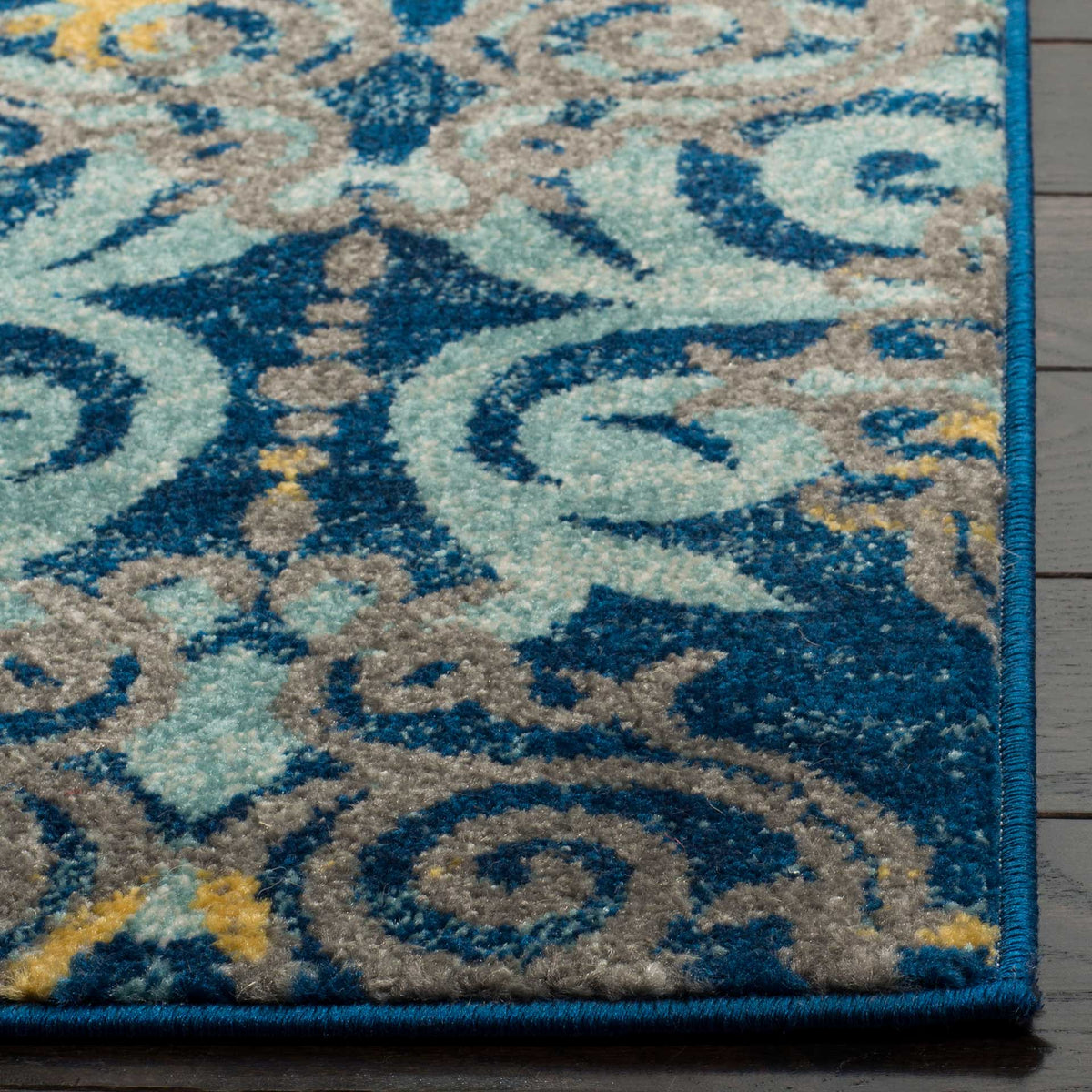Soft aqua scrollwork meets a dark blue field and a neatly bound rug corner.
